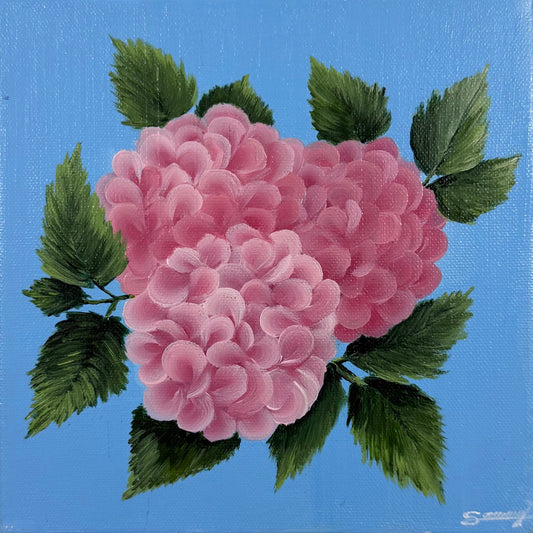 A square canvas painting featuring pink flowers and green leaves on a light blue background, mounted on a textured beige wall.