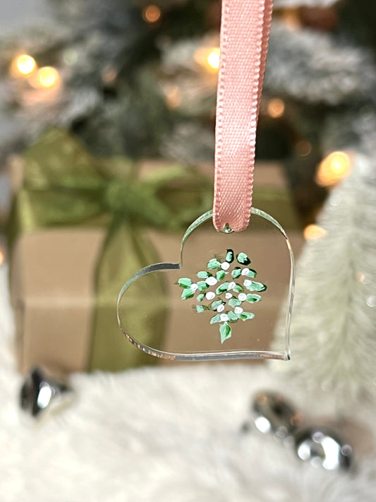clear acrylic heart ornament with hand painted mistletoe and a pink ribbon