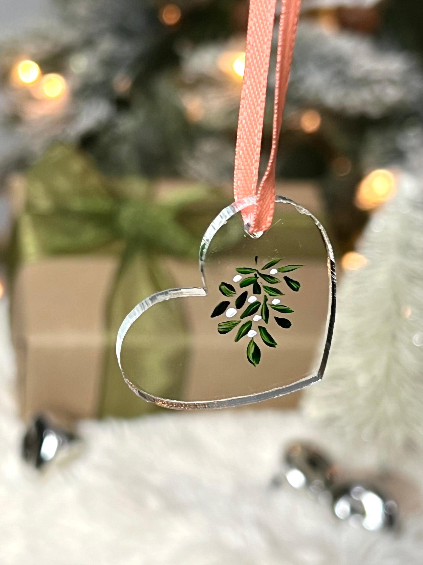 clear acrylic heart ornament with hand painted mistletoe and a pink ribbon