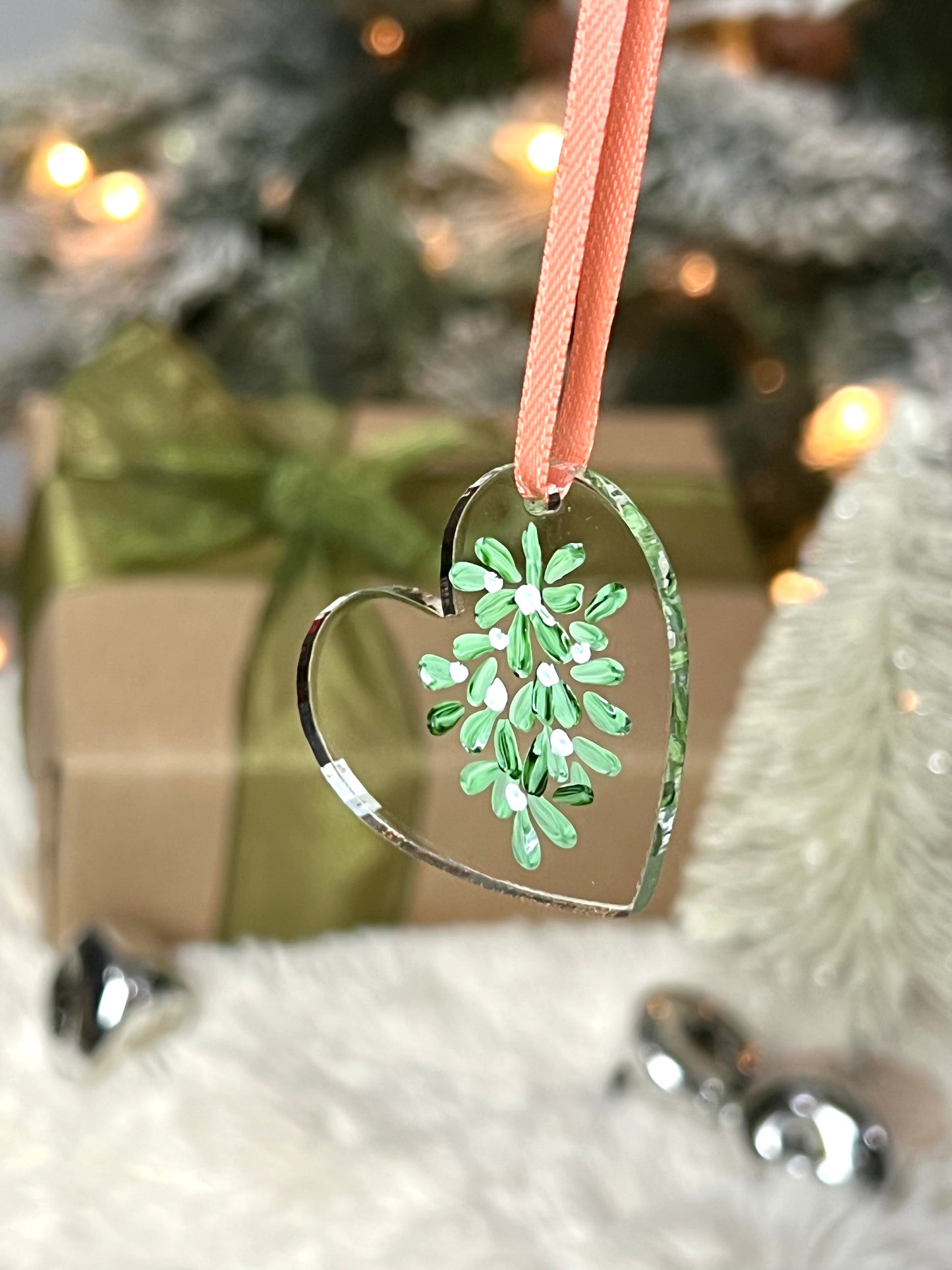 clear acrylic heart ornament with hand painted mistletoe and a pink ribbon
