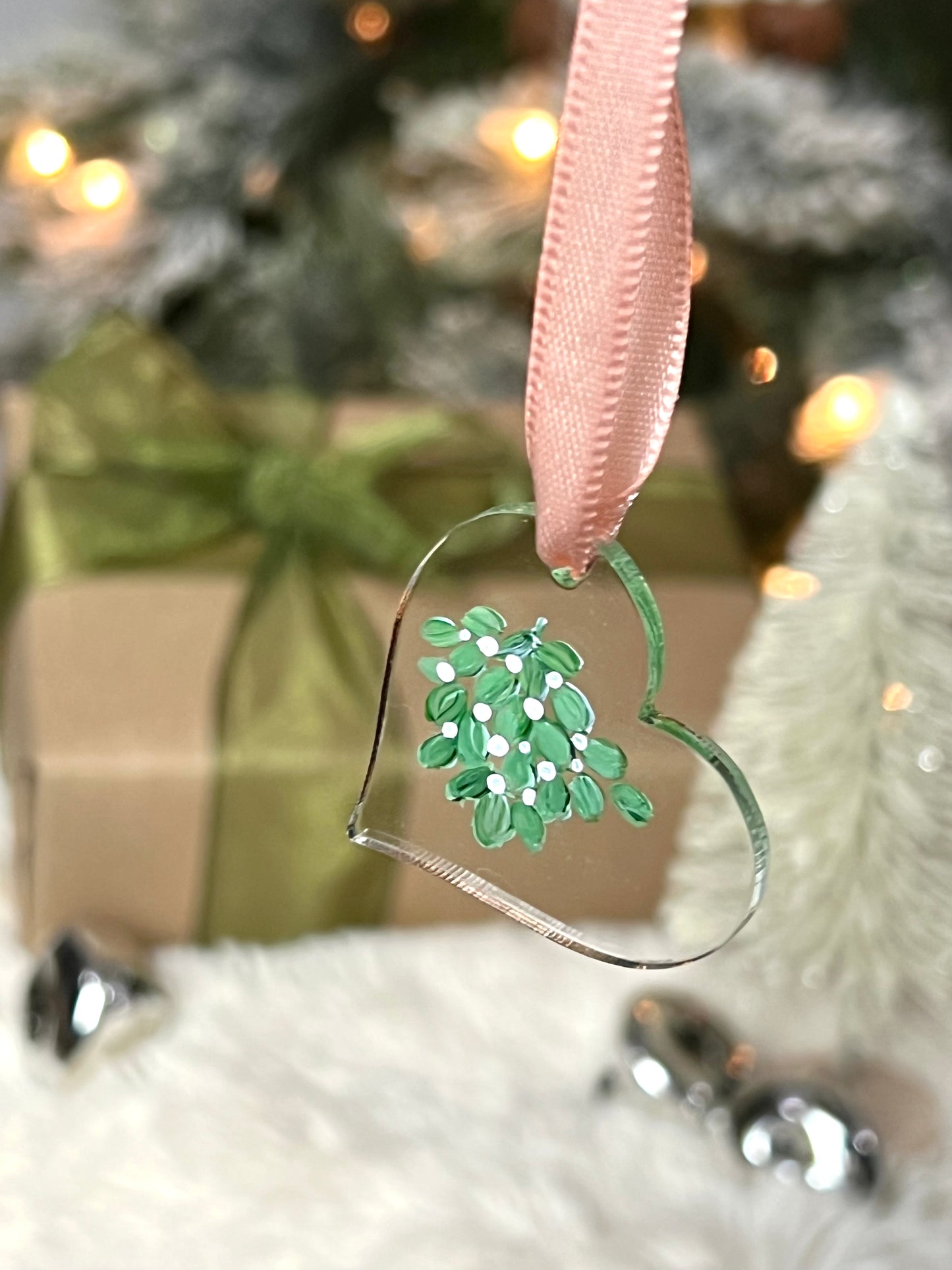 clear acrylic heart ornament with hand painted mistletoe and a pink ribbon