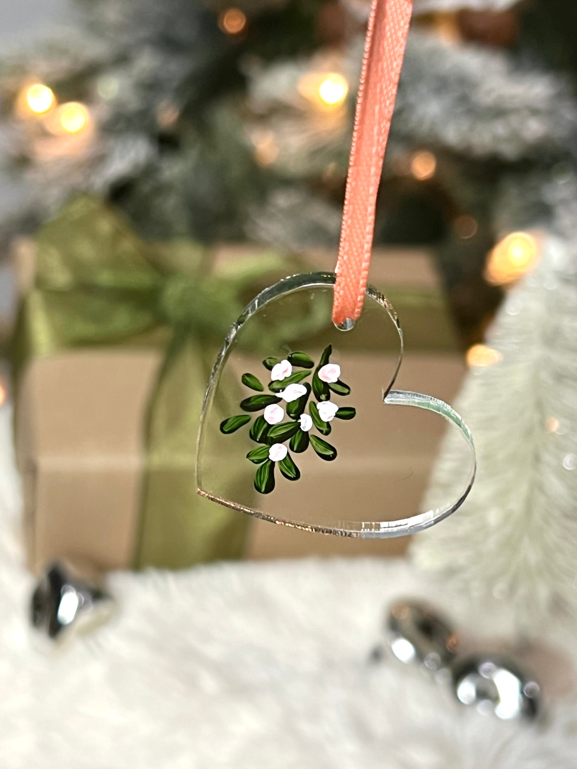 clear acrylic heart ornament with hand painted mistletoe and a pink ribbon
